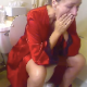 A mature woman wearing a red robe takes a shit and a piss while sitting on a toilet. She wipes when finished. No loud pooping sound is heard, but it is obviously smelled. No product shown. Over 3.5 minutes.